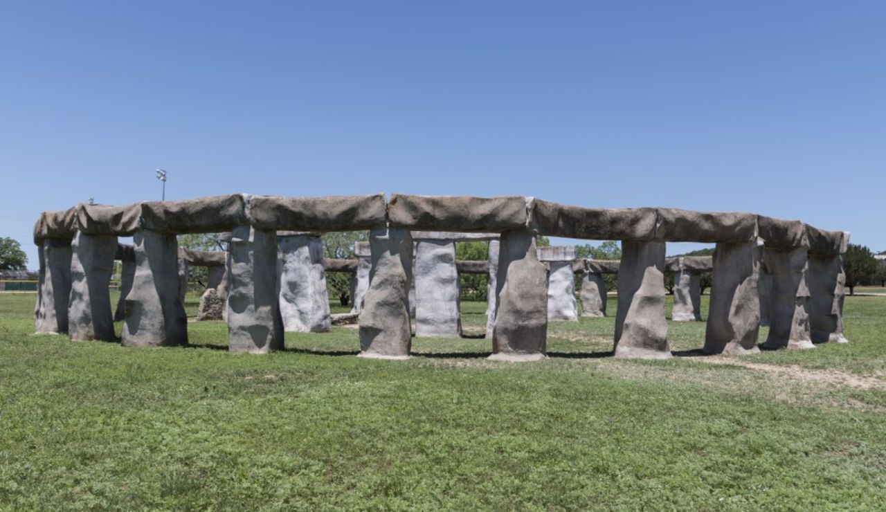 Replica of Stonehenge known as Foamhenge in Texas, featuring large foam blocks arranged in a circular formation on a grassy field under a clear blue sky.