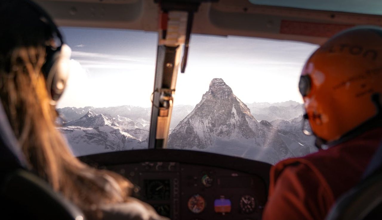 View from a cockpit flying over the Swiss Alps, with pilots observing the iconic Matterhorn peak surrounded by snow-covered mountains.