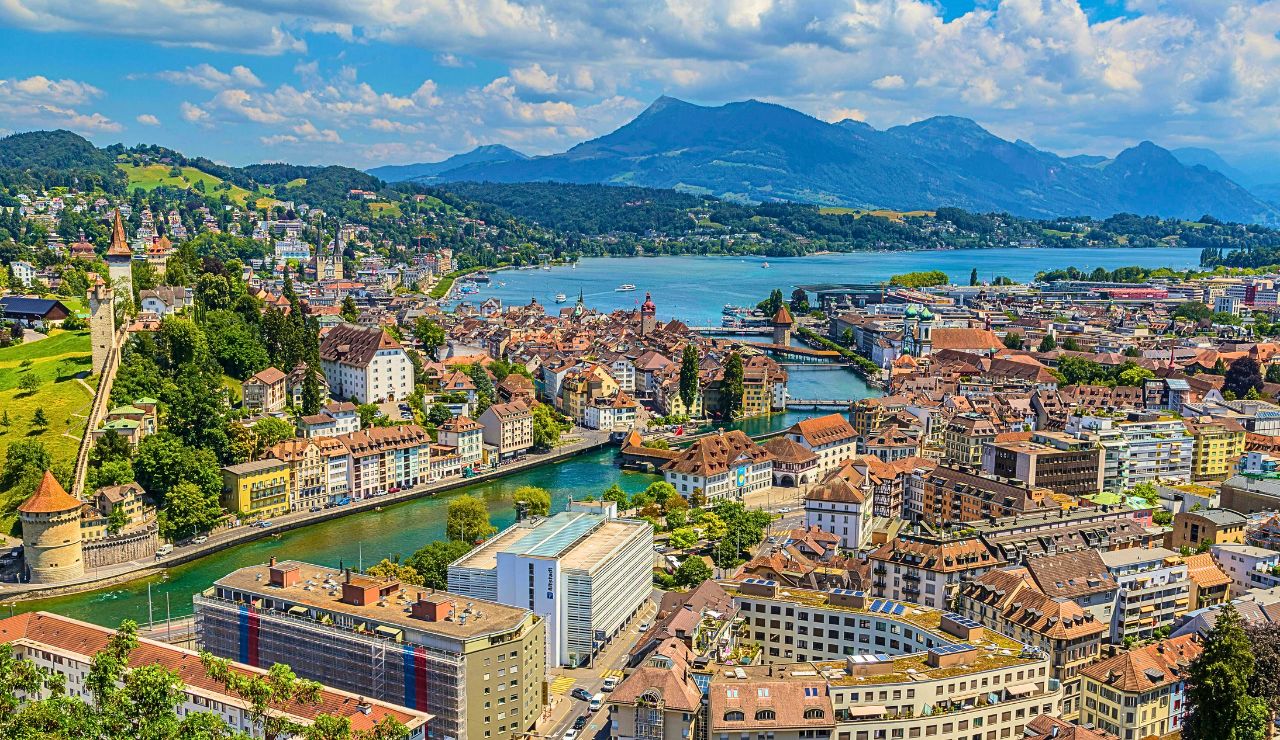 Swiss lake with snowy mountains and a peaceful town.