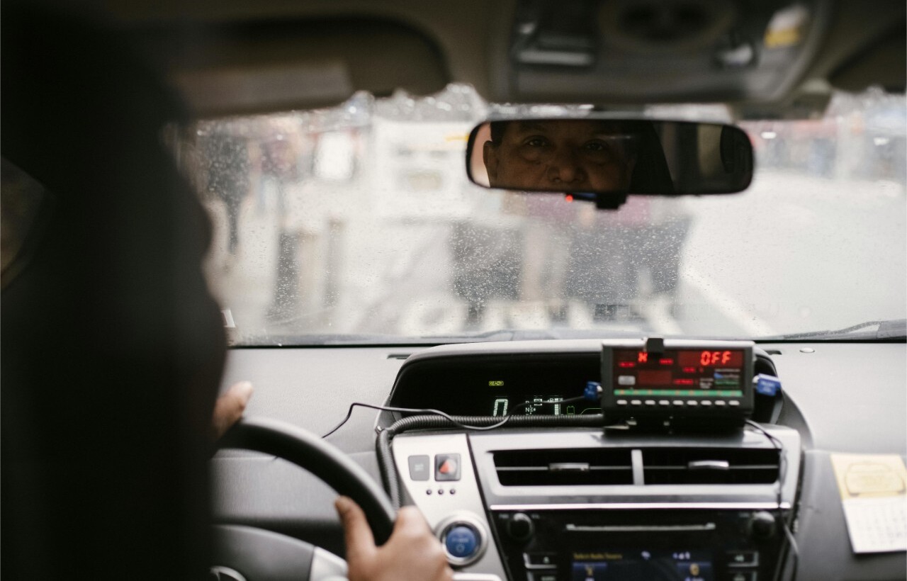 Taxi driver seen through rearview mirror.