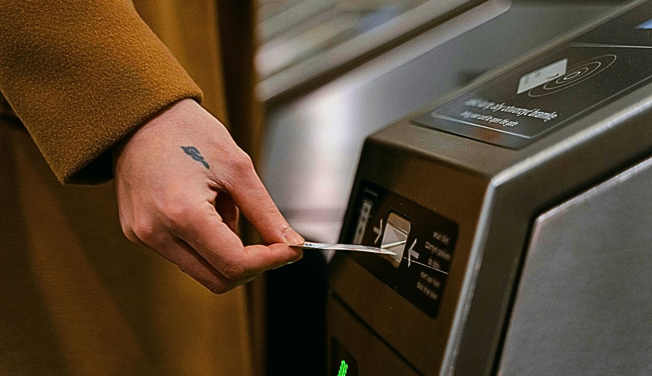 A small ticket validation machine near a platform with a traveler inserting a paper ticket.