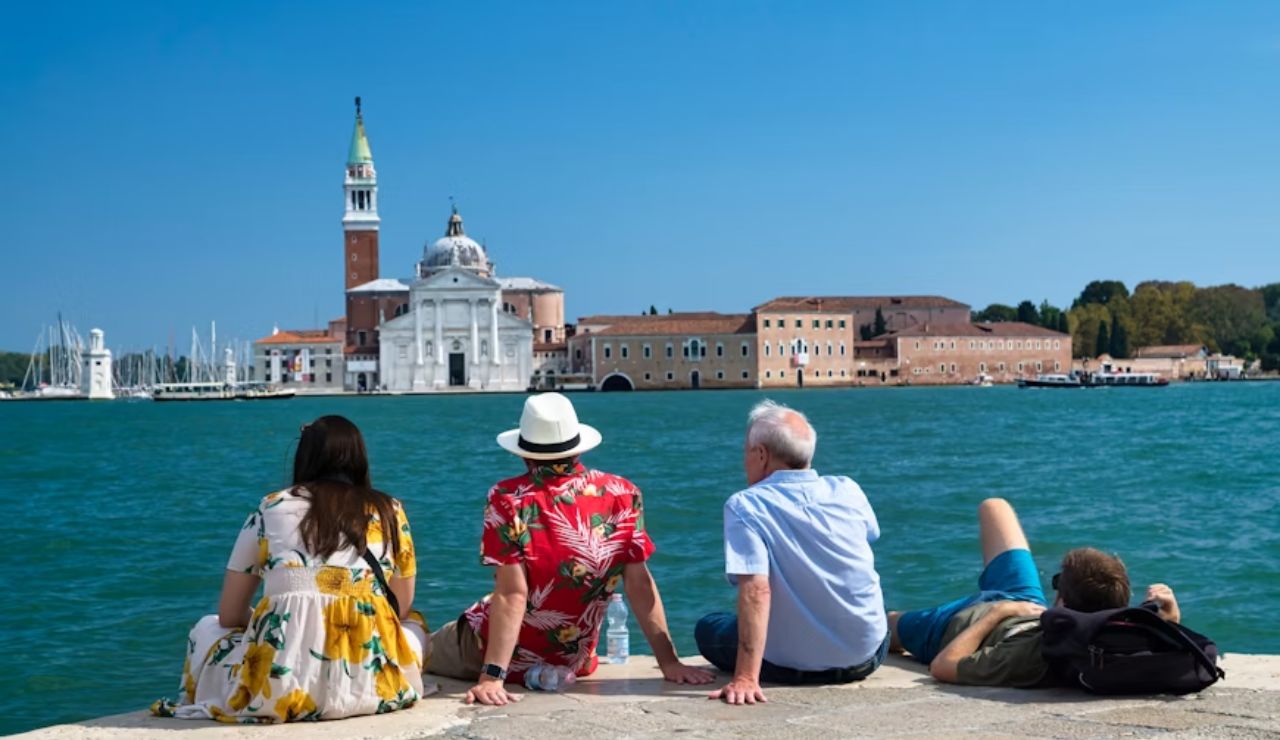 Tourists relaxing by the waterfront with view of San Giorgio Maggiore in Venice.
