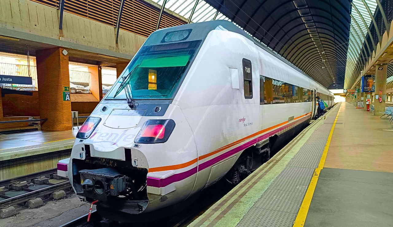 Overhead signage showing “Vía 5” and digital boards in a modern Spanish train station concourse.