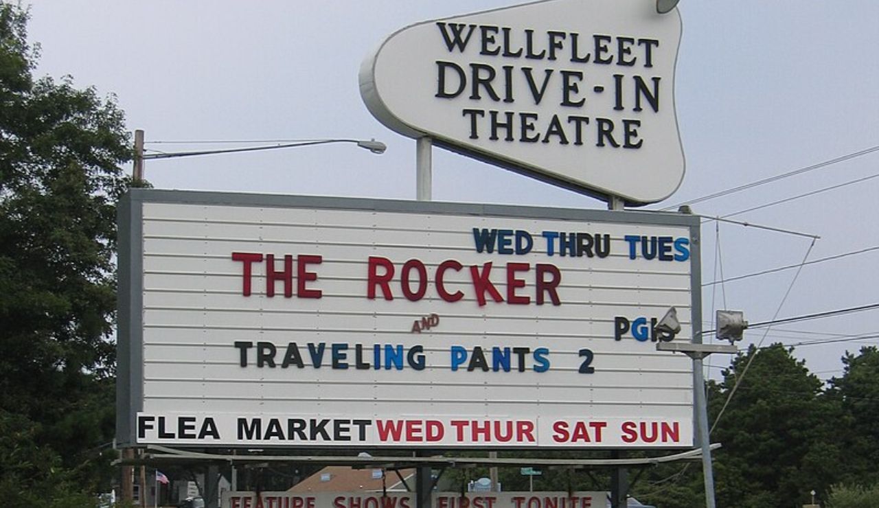 Wellfleet Drive-In Theatre marquee sign showing movies The Rocker and Traveling Pants 2, with flea market days listed below.