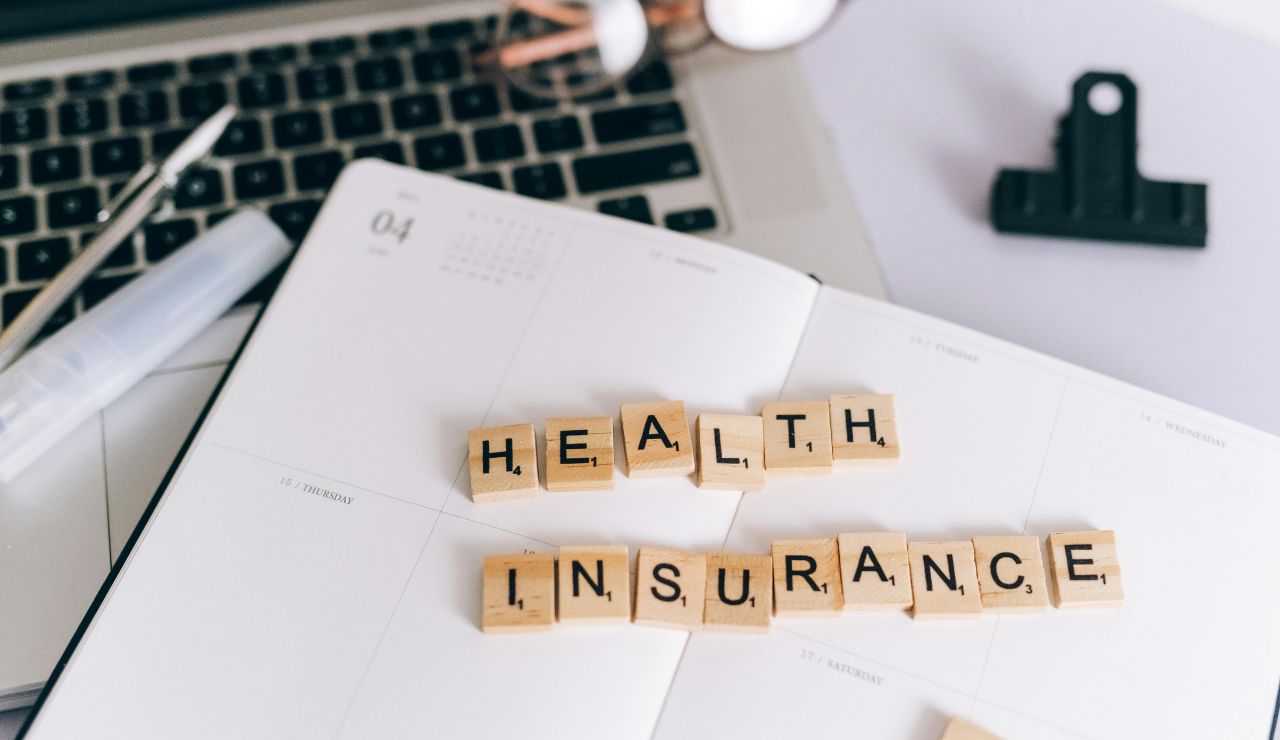 Health insurance spelled with wooden letter tiles on a planner near laptop