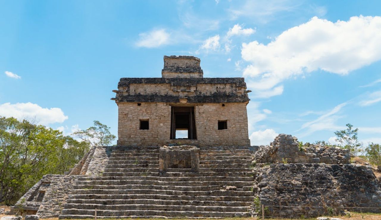 Ancient Mayan temple at Ek' Balam archaeological site in Yucatán, Mexico, under a bright blue sky.