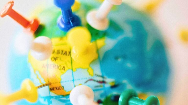 A globe displays colorful push pins locations.