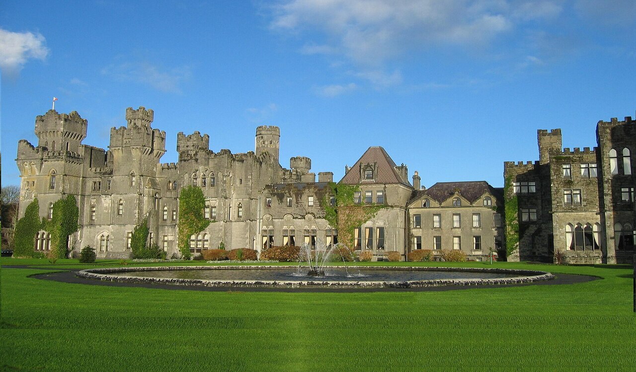 Ashford Castle with central fountain and green lawn in Ireland.