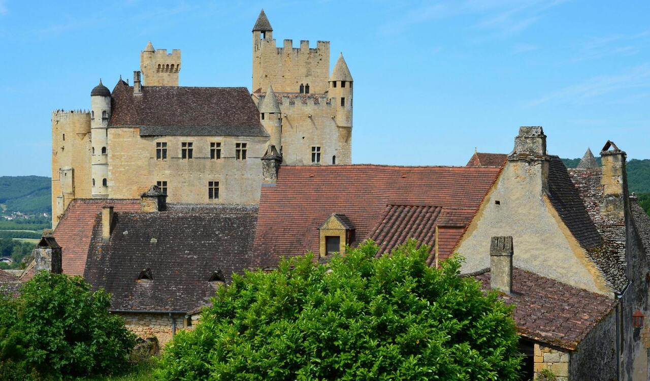 Château de Bagnols castle behind village rooftops in Beaujolais, France.