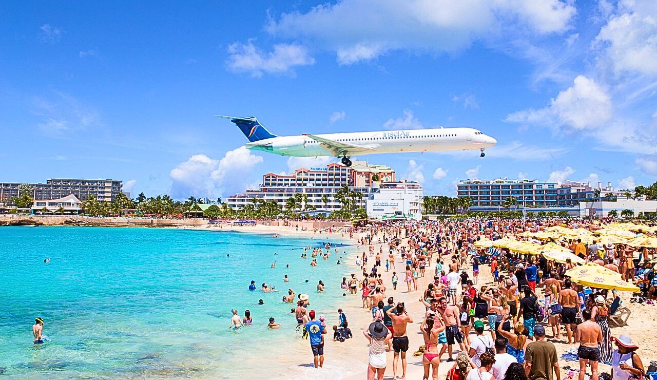 A jetliner flying low over sunbathers at Maho Beach just before landing.