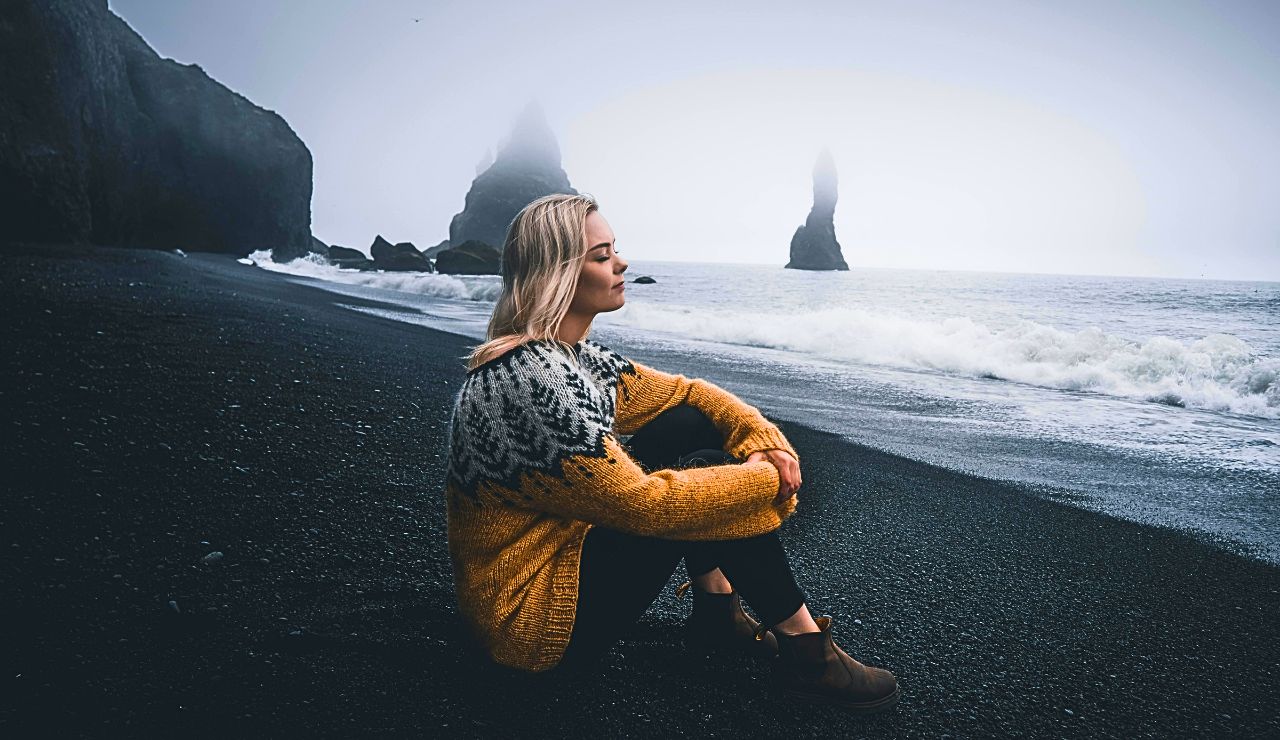 Reynisfjara’s black volcanic sand and basalt columns under a misty sky with waves crashing dramatically.