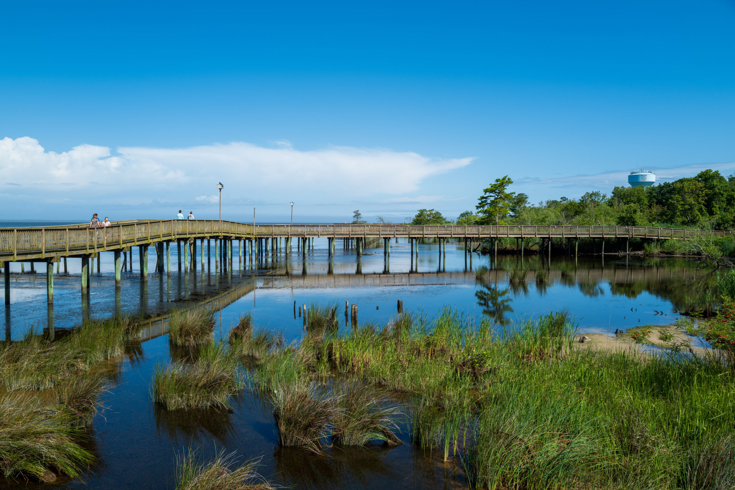 A wide angle photo of the boardwalk that crosses over the water of Currituck Sound in Duck, NC. It's one of the most romantic places to stay in North Carolina!