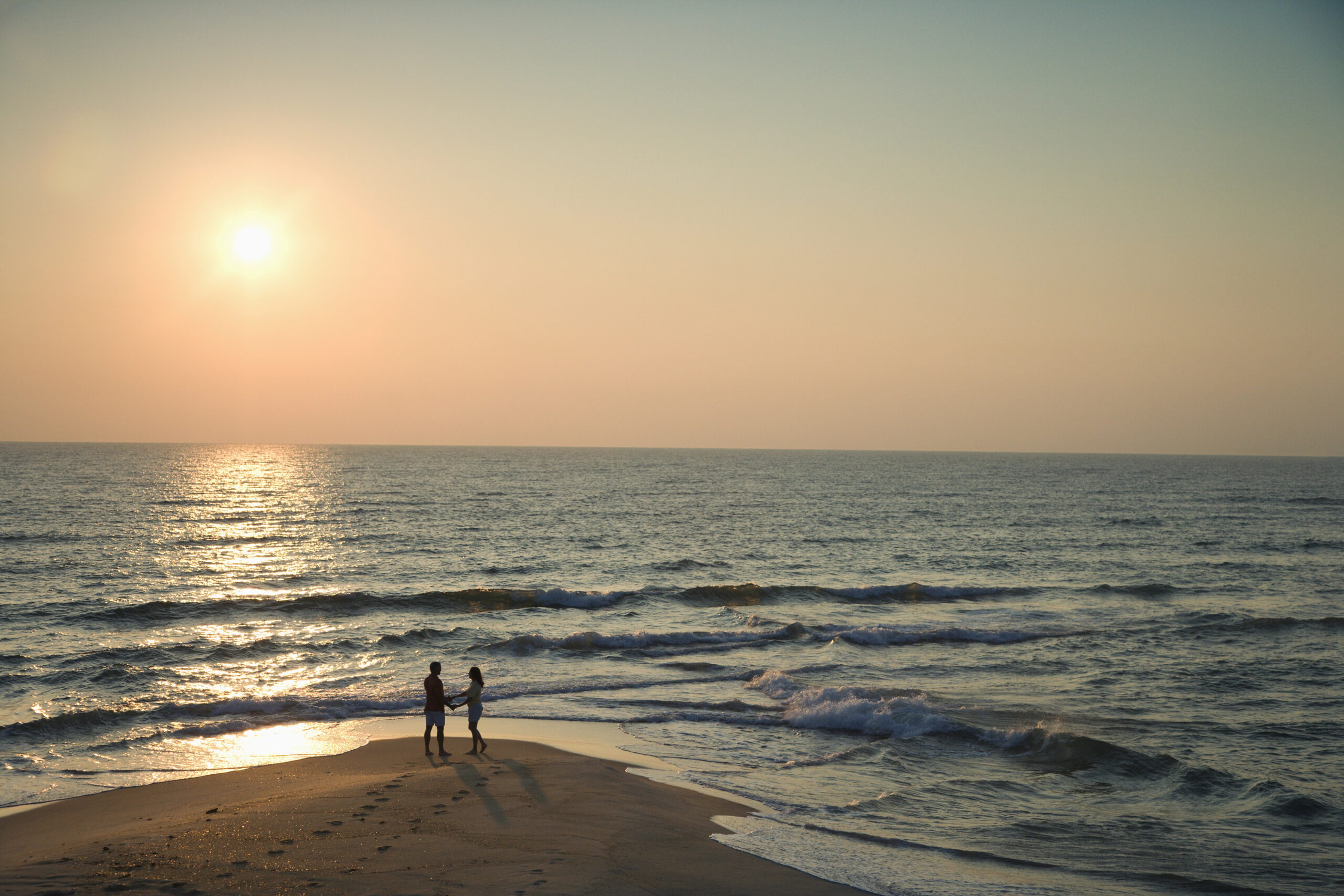 Couple in silhouette on a beach in North Carolina at sunset.