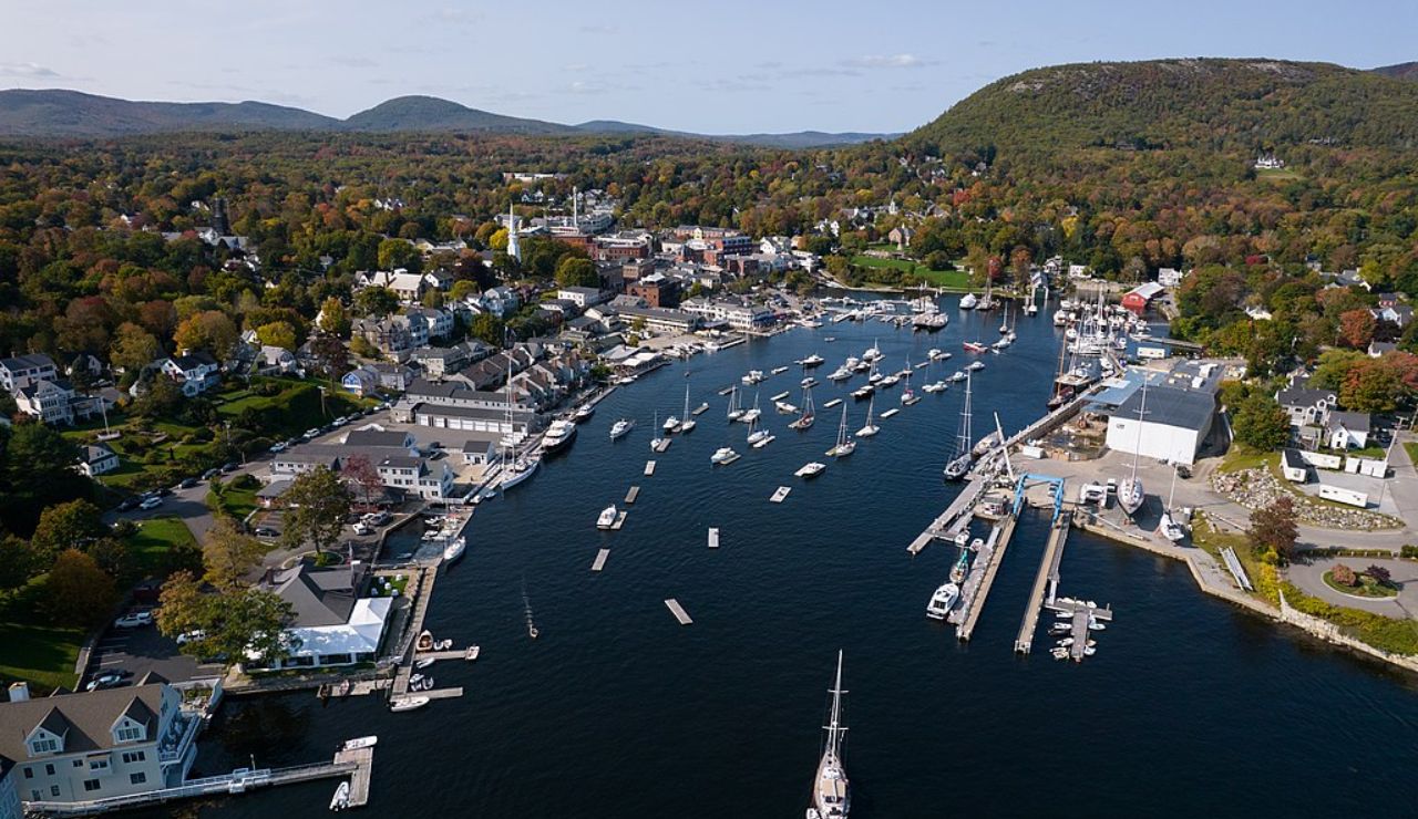 Aerial view of Camden Harbor in Maine with boats and surrounding autumn trees.
