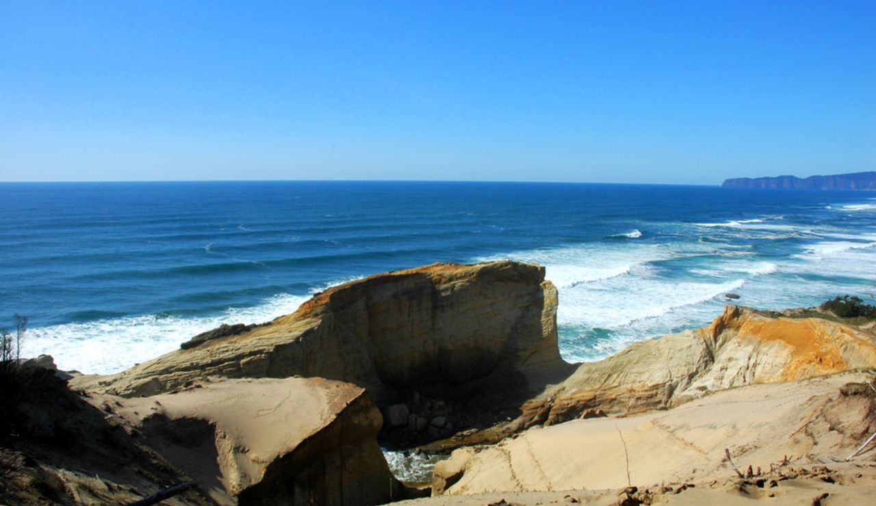 This is a view of Cape Kiwanda on the Oregon Coast, known for its dramatic sandstone cliffs, scenic ocean views, and popular surfing spots.
