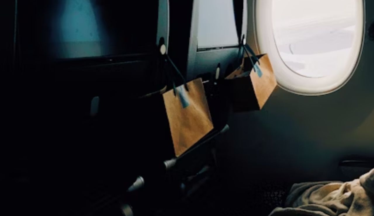 irplane seats with screens and a window, cozy blanket in view.