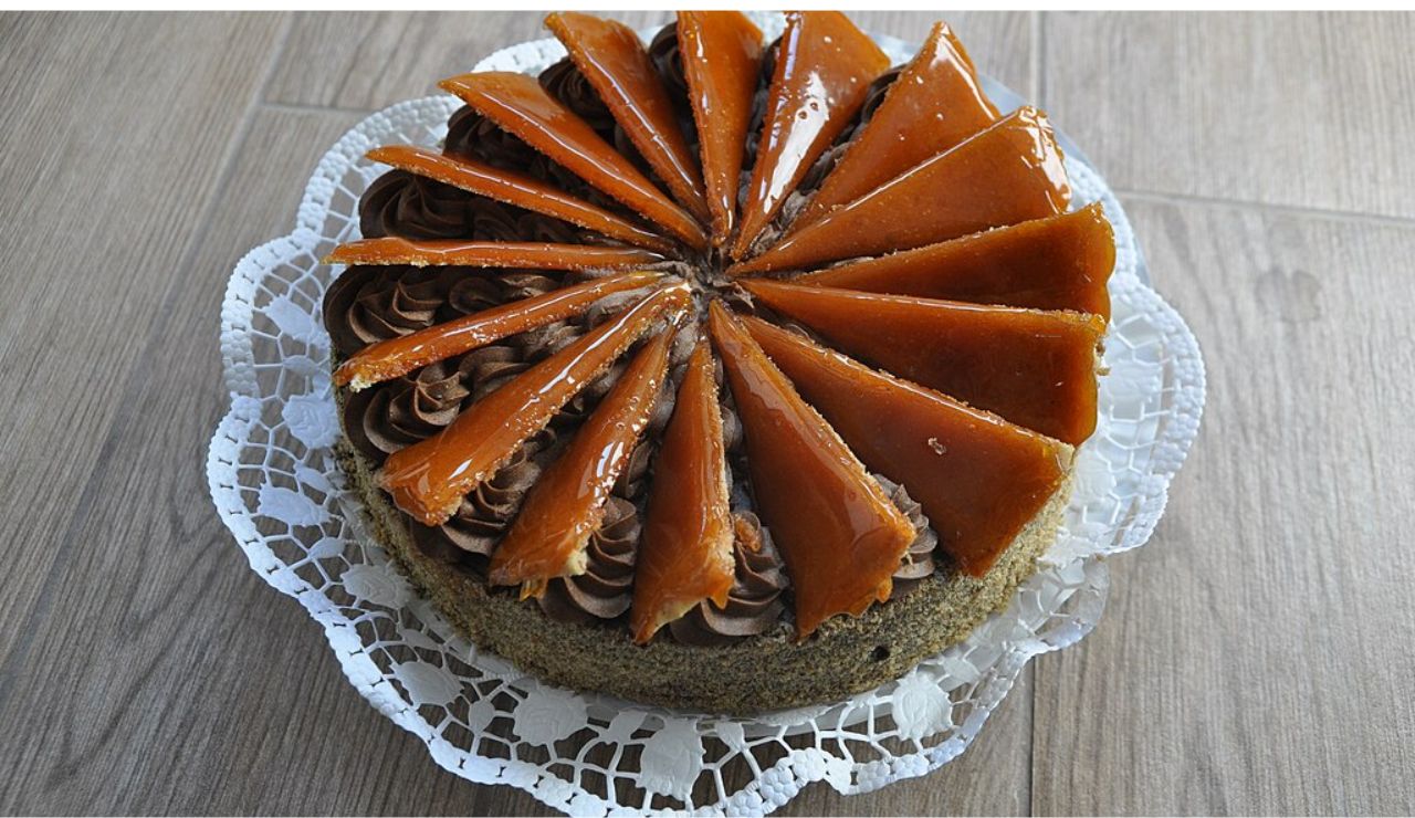 Dobos Torte, a traditional Hungarian layered sponge cake topped with caramel slices and chocolate buttercream, served on a lace doily.