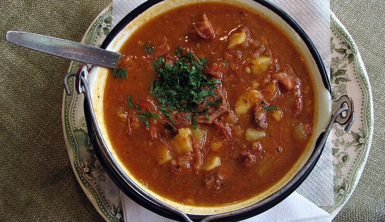 Bowl of Hungarian gulyás soup with beef, potatoes, and parsley.