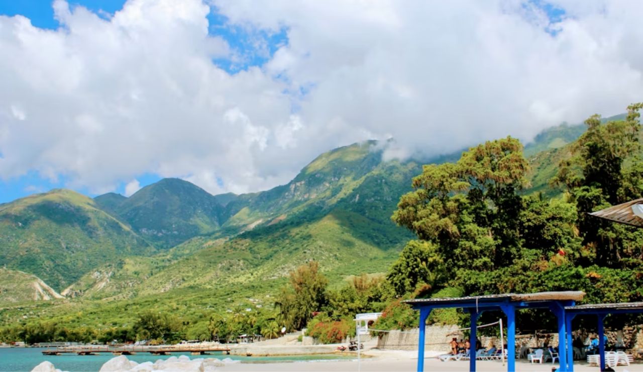 Tropical beach with blue huts and green mountains in Haiti.