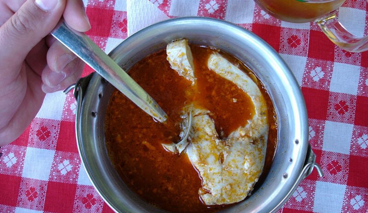 Traditional Hungarian fish soup (halászlé) served in a metal bowl with a fish steak in red paprika broth.