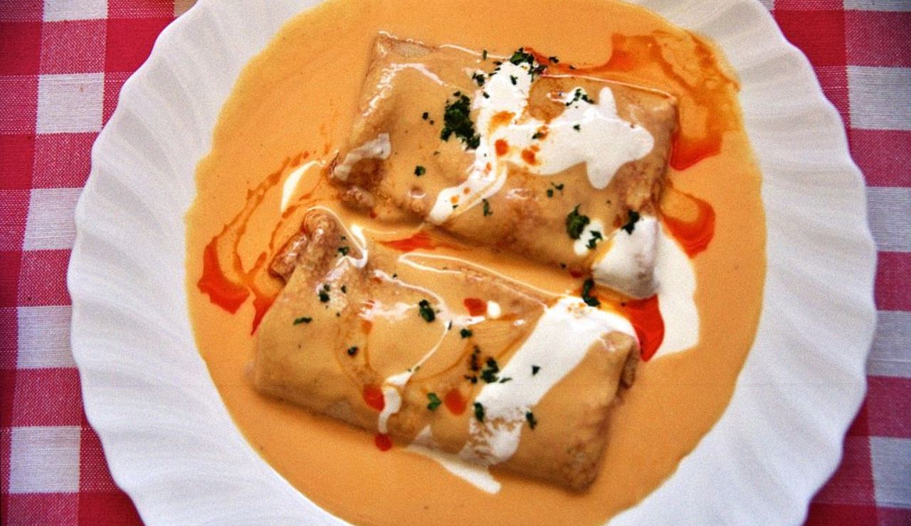 Hungarian Hortobágyi palacsinta stuffed crepes topped with paprika sauce and sour cream.