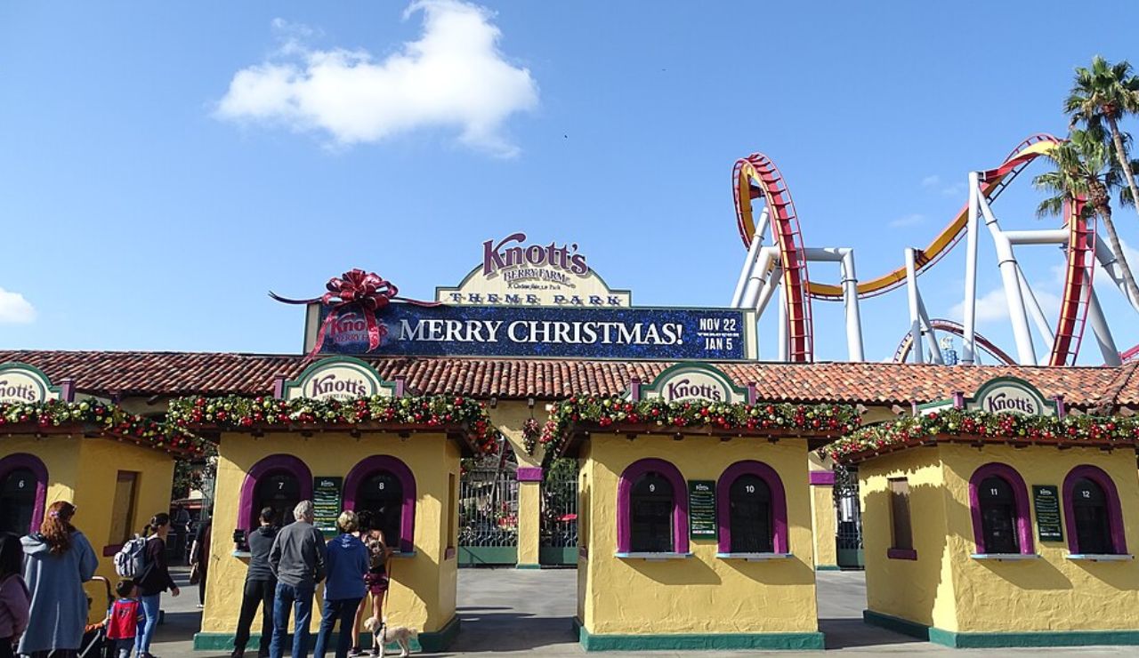 Entrance of Knott's Berry Farm theme park decorated for Christmas, with roller coaster tracks in the background.