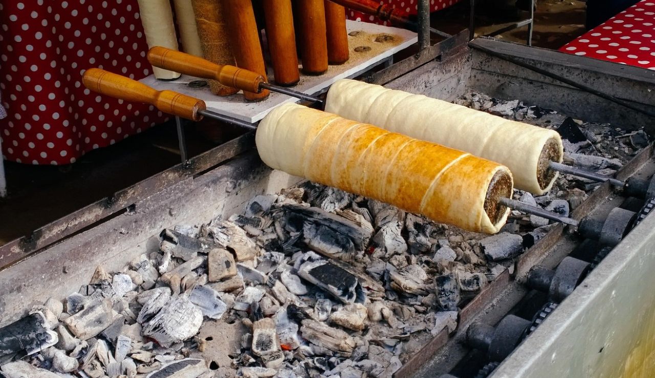 Traditional Hungarian chimney cakes (kürtőskalács) being baked over hot charcoal on rotating spits.