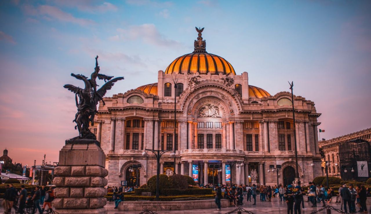 Palacio de Bellas Artes in Mexico City with people gathered in front during sunset.