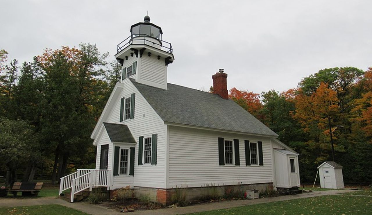 Crisp Point-style white lighthouse building surrounded by autumn trees in Michigan.