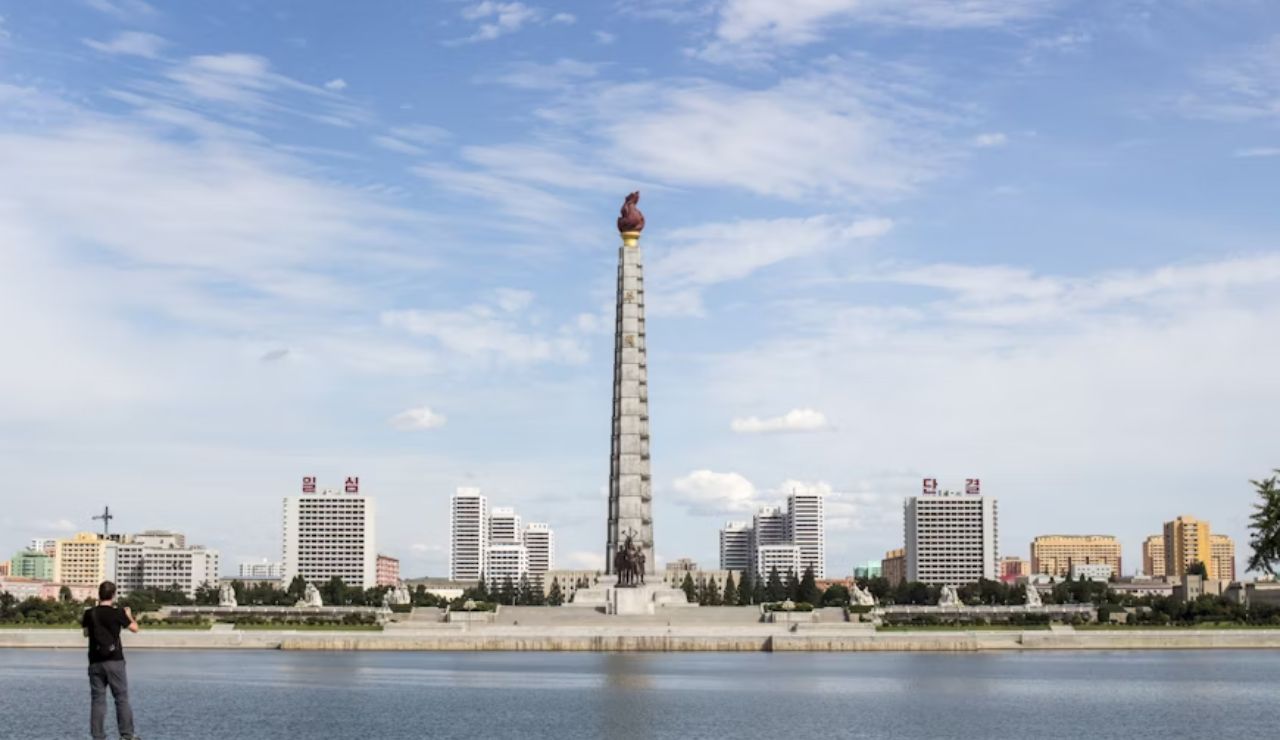 Man photographing the Juche Tower across the Taedong River in Pyongyang, North Korea.