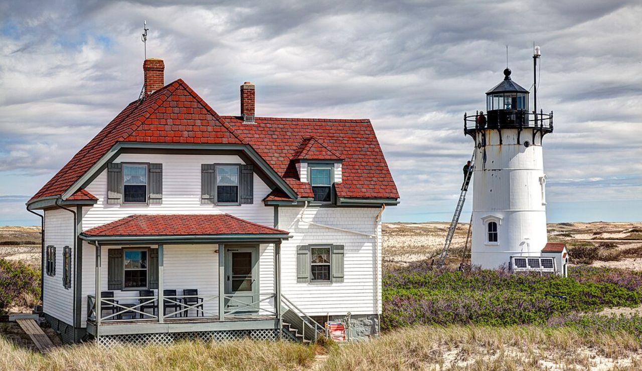 Race Point Light Station in Massachusetts with a white keeper's house and round lighthouse set among coastal sand dunes.