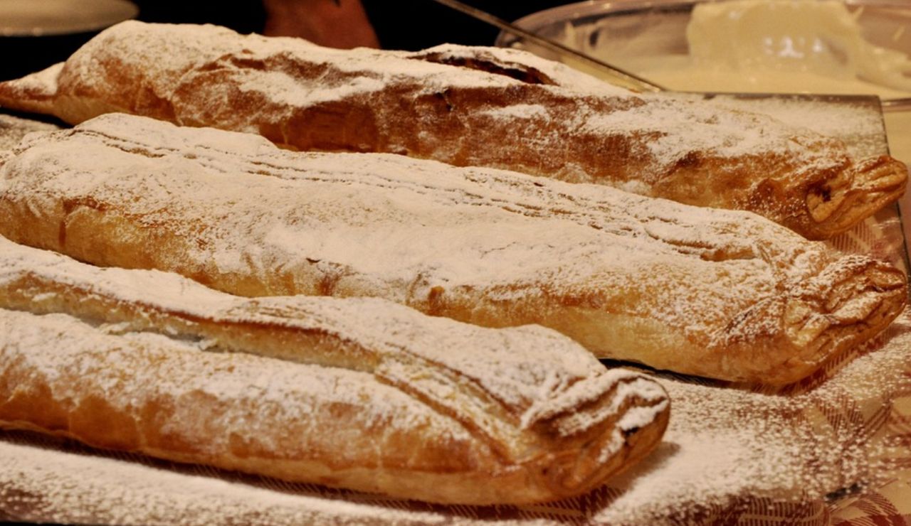  Hungarian apple strudel pastries dusted with powdered sugar on a tray.
