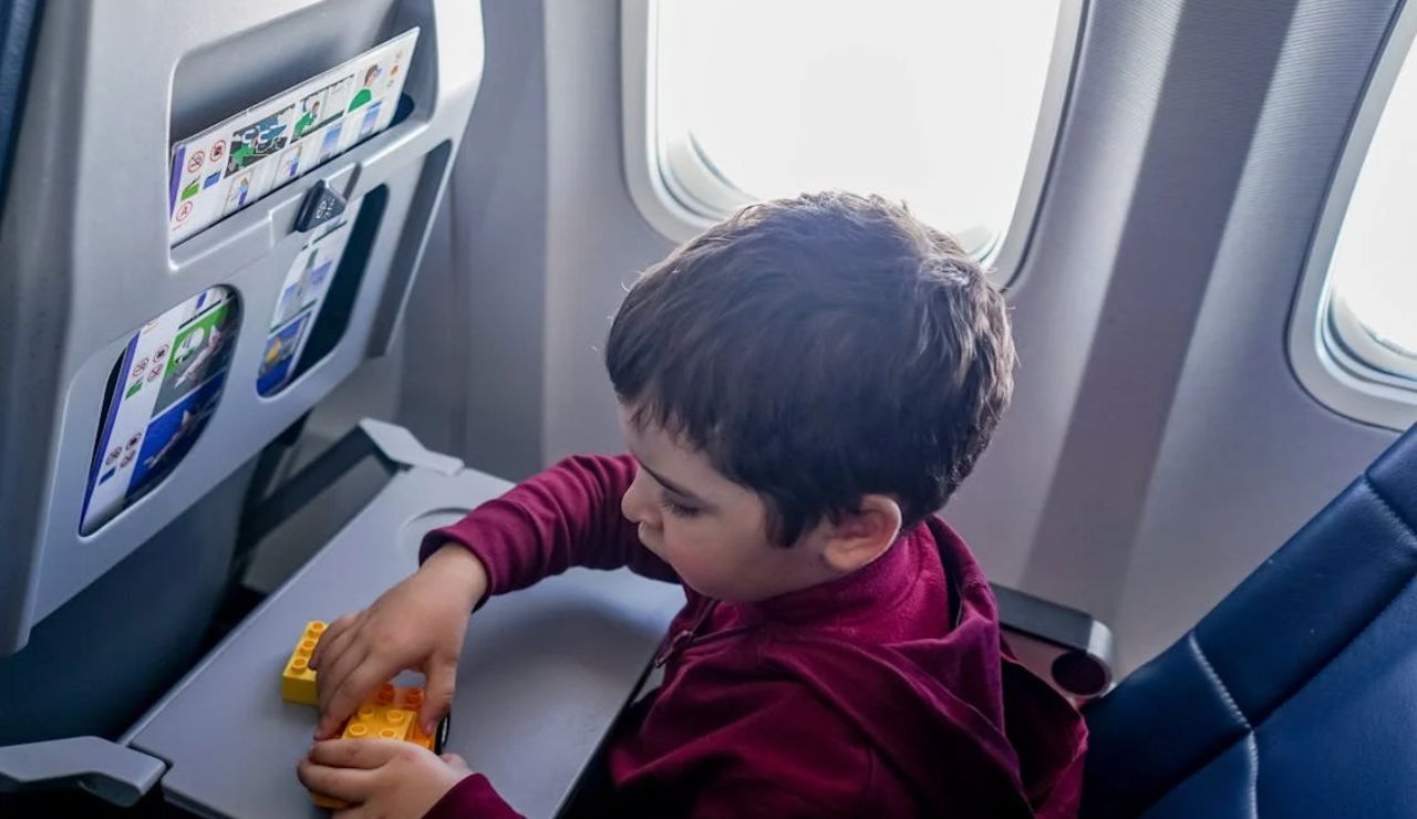 Young child playing with toy blocks on an airplane tray table during a flight.