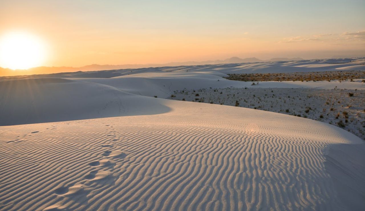 A golden sunset glows over the rippled gypsum dunes of White Sands, New Mexico.