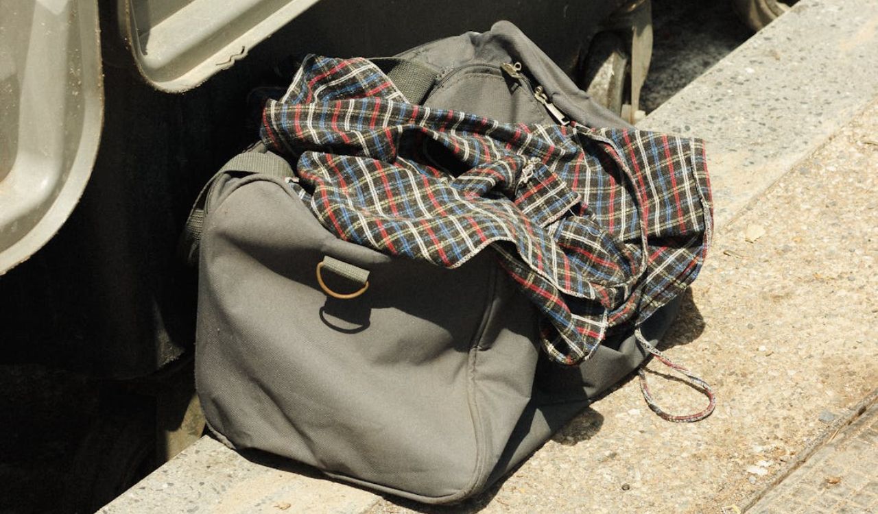 Unattended duffel bag and plaid shirt on a train platform, symbolizing the travel mistake of packing only for warm weather