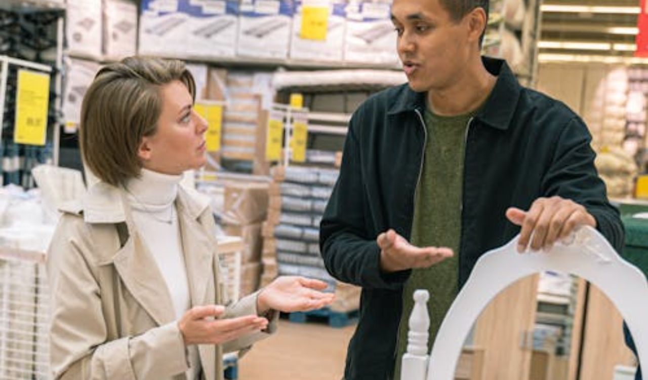 Two people discussing a furniture purchase in a large retail store, illustrating typical shopping behavior in supermarkets instead of local markets