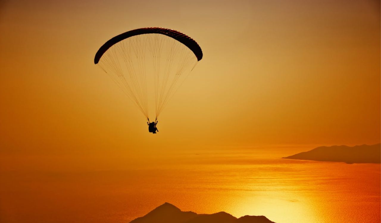Paragliding over coastal mountains at sunset, highlighting the challenges of high altitude adventure travel in South America