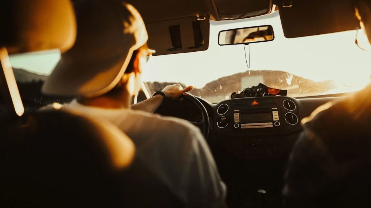 Person driving a car at sunset with a passenger beside them