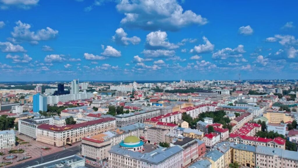 Aerial view of Minsk, Belarus with colorful rooftops and scattered clouds in a bright blue sky.
