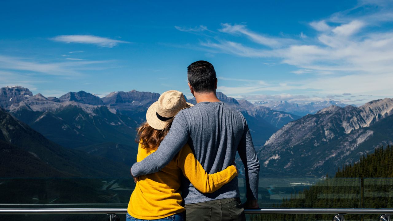 Couple embracing while enjoying a scenic mountain view from a lookout point.