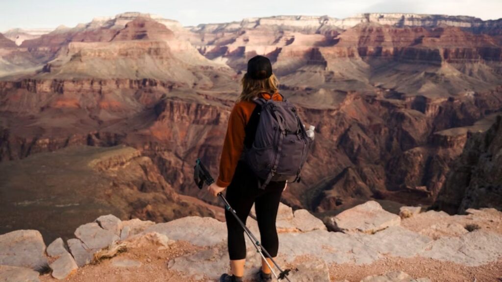 Hiker with backpack and trekking poles overlooking the Grand Canyon.