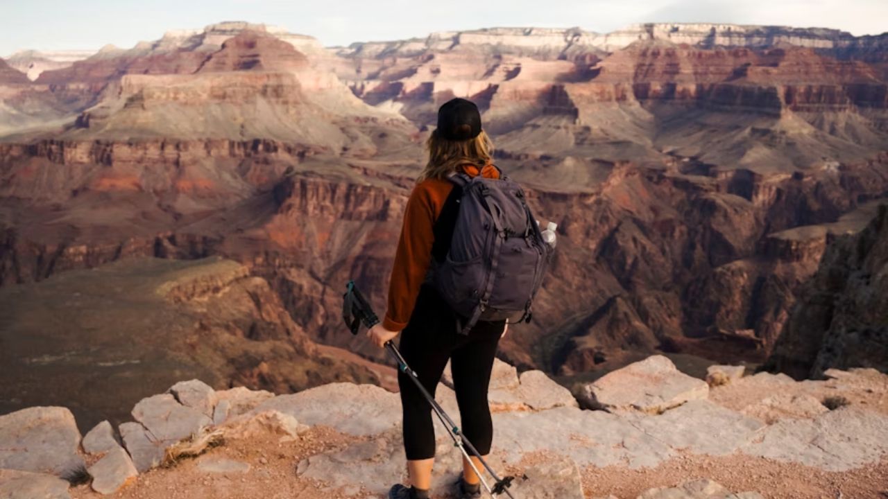 Hiker with backpack and trekking poles overlooking the Grand Canyon.