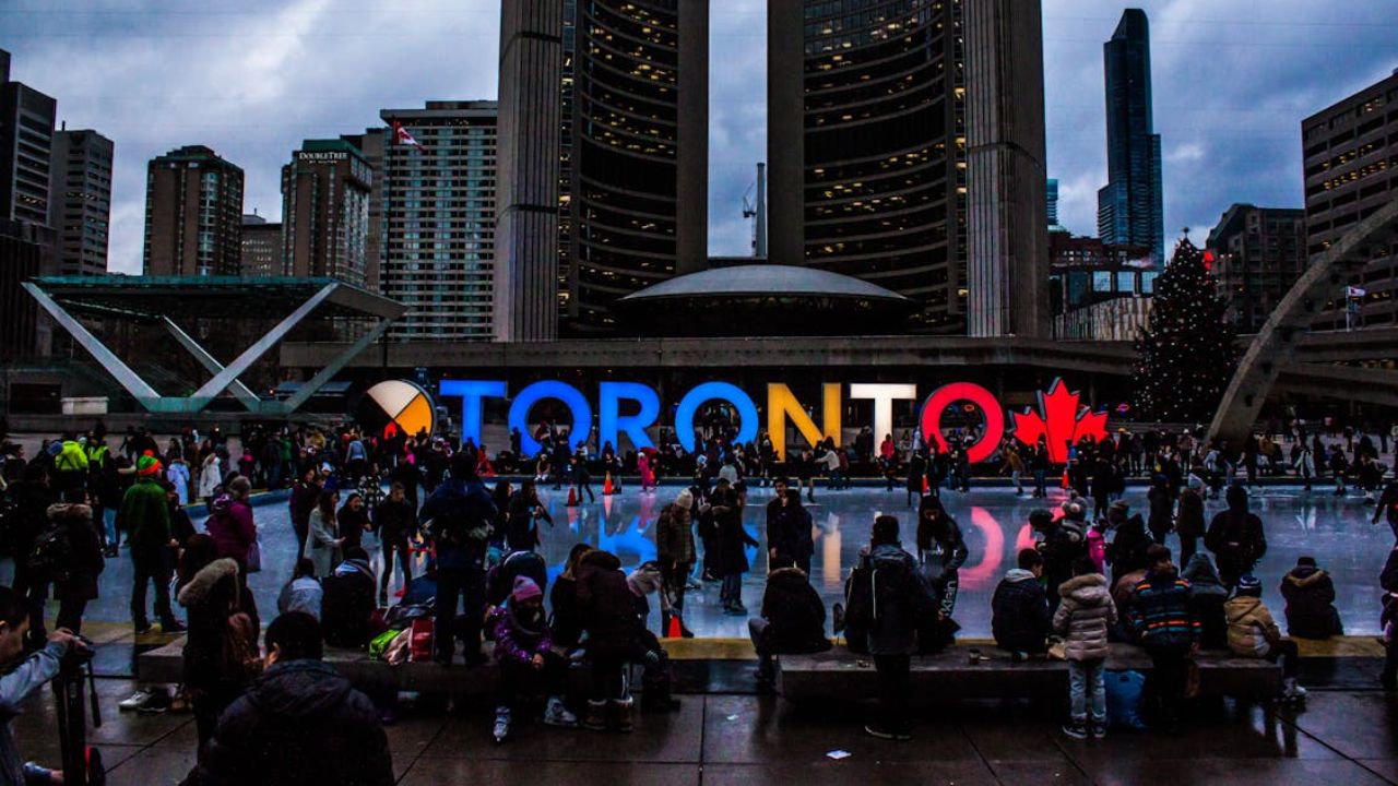 Crowd at Toronto’s Nathan Phillips Square with lit-up sign and ice rink