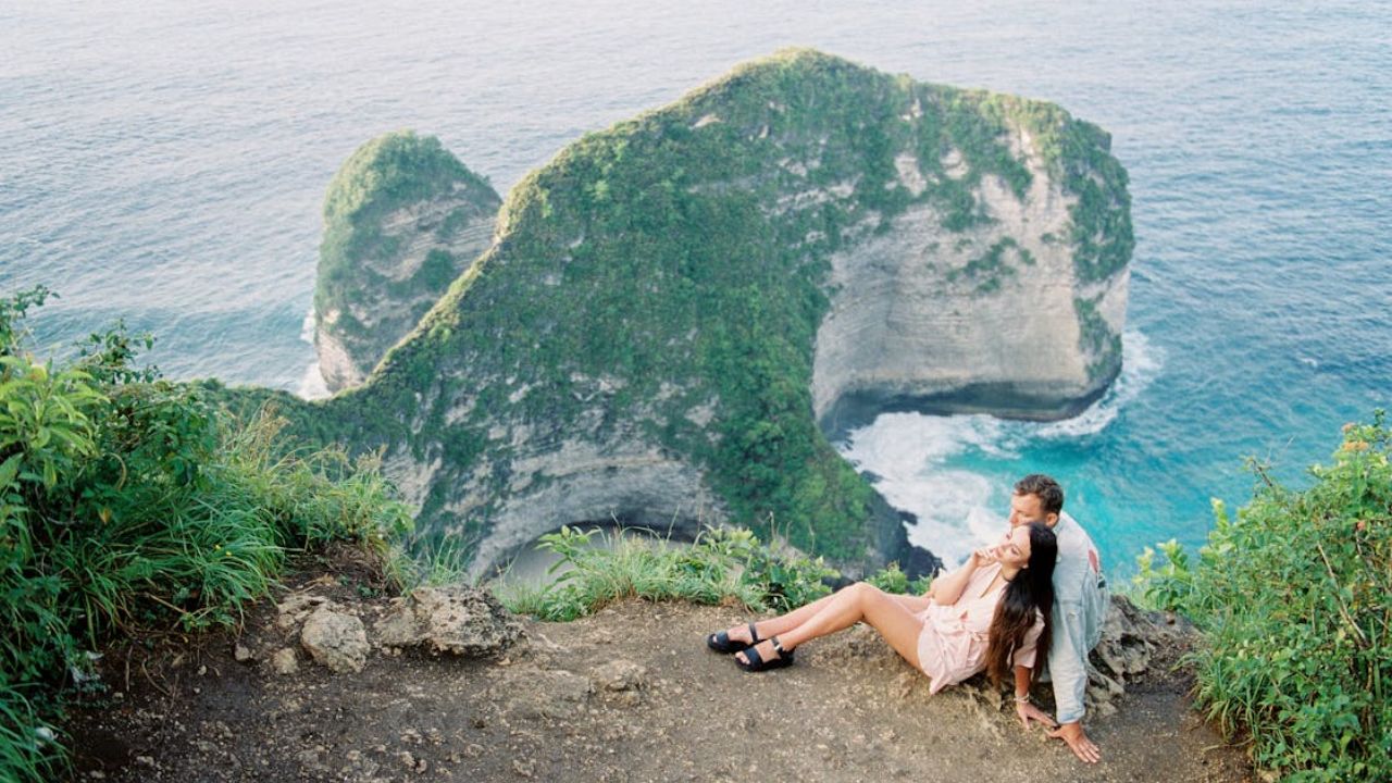 Couple sitting on a cliffside overlooking the ocean at a romantic tropical destination
