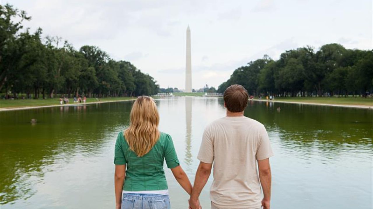 Couple holding hands while looking at the Washington Monument across the Reflecting Pool.