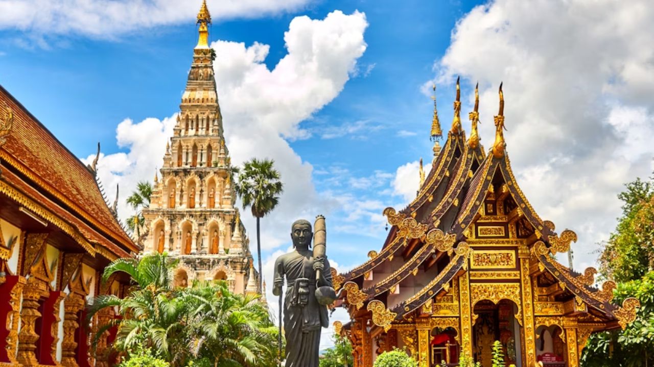 Ornate Buddhist temple and golden stupa in Thailand under a bright sky, representing cultural preservation in tourism.