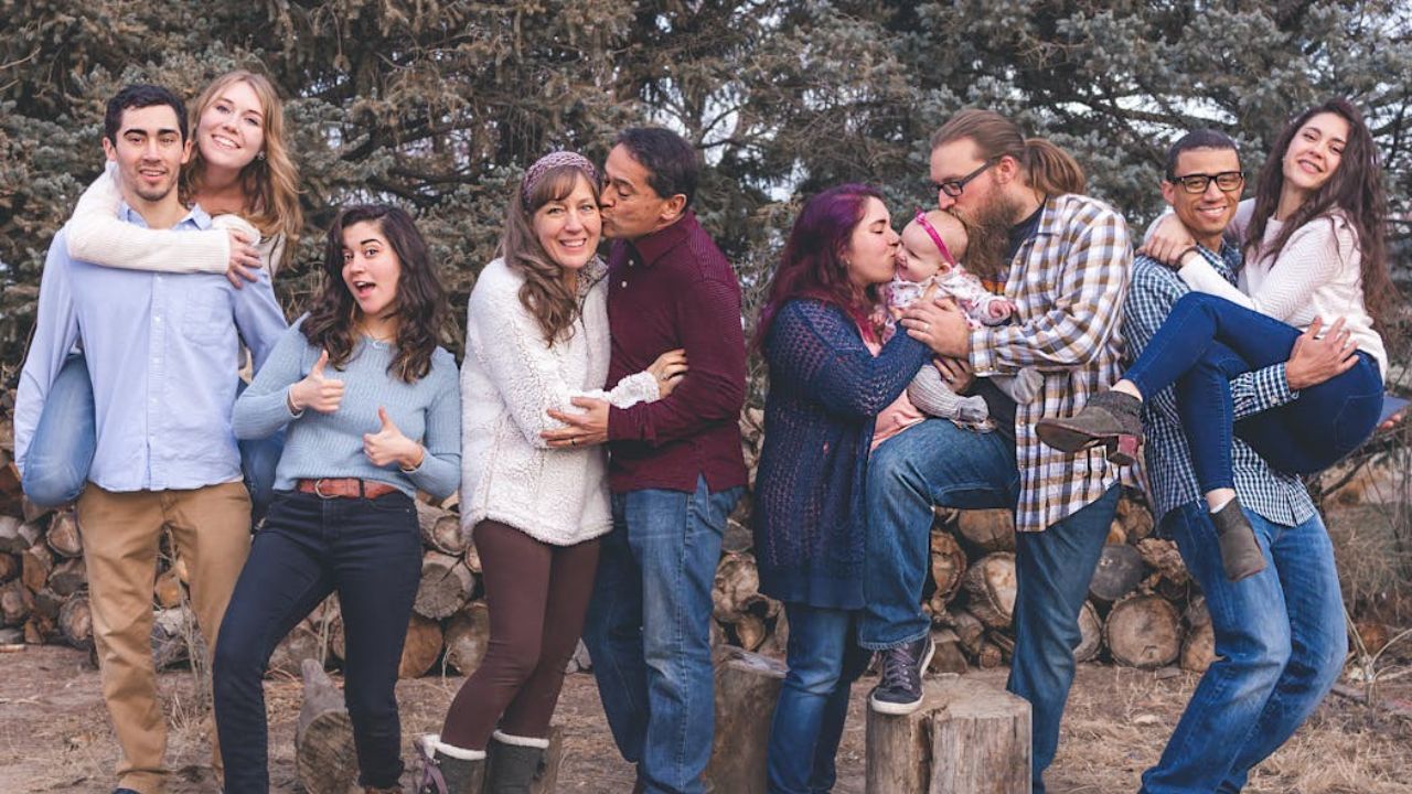 Group of couples posing playfully outdoors with trees and logs in the background