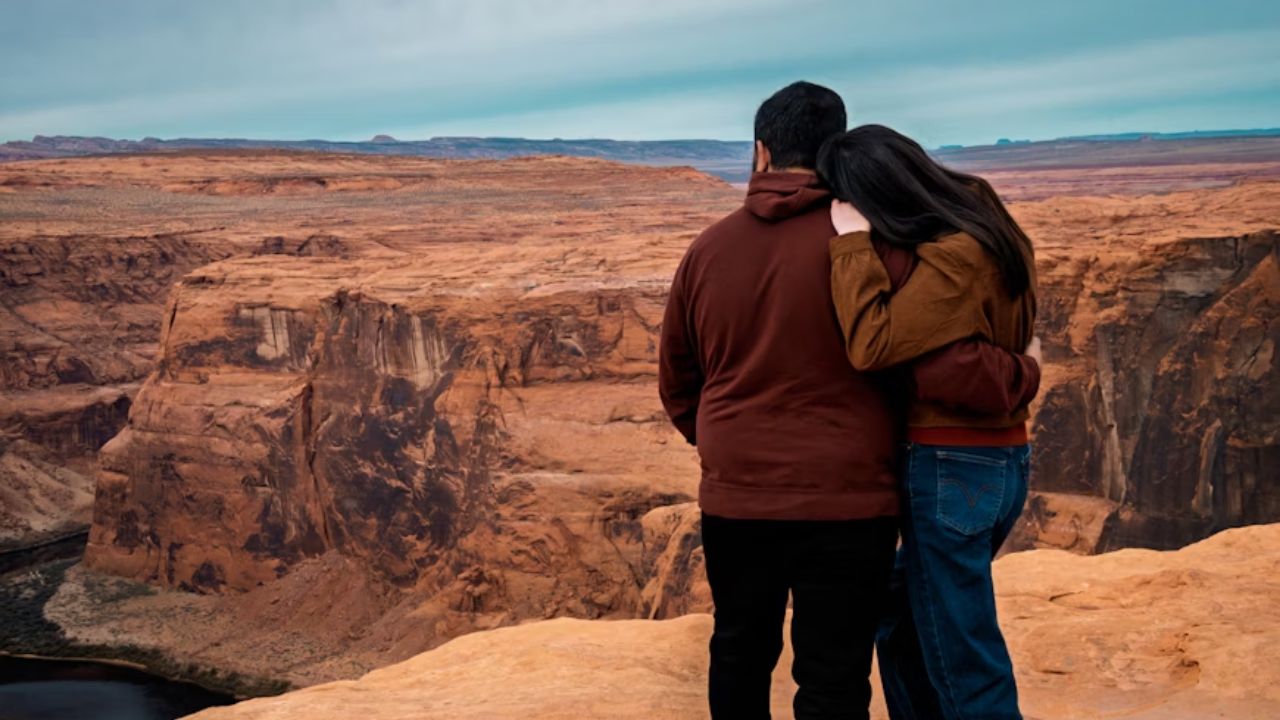 Couple embracing while overlooking a vast desert canyon landscape.