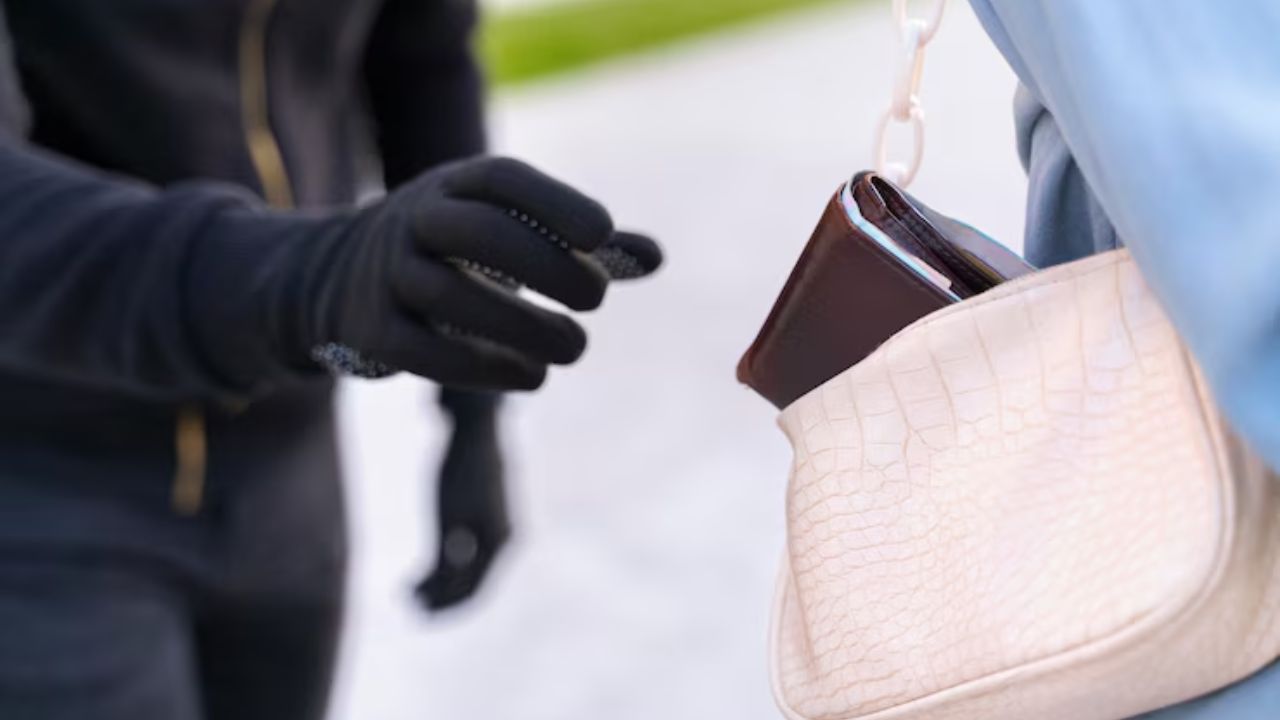 Gloved hand stealing a wallet from an open handbag