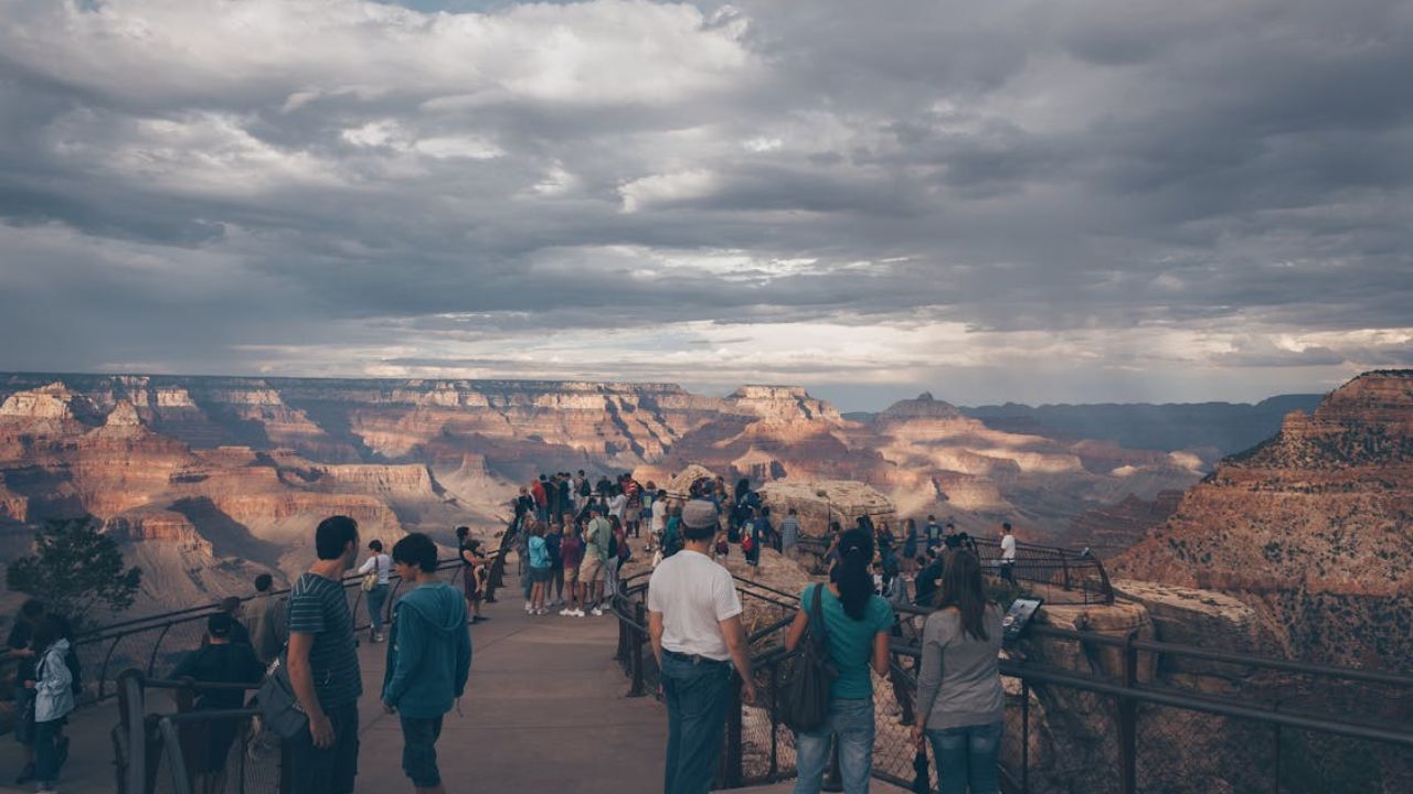 Tourists gathered at a scenic Grand Canyon viewpoint under a cloudy sky